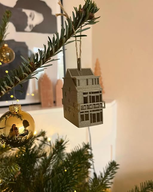 Goudkleurig gebouwd huis aan een kerstboomtak