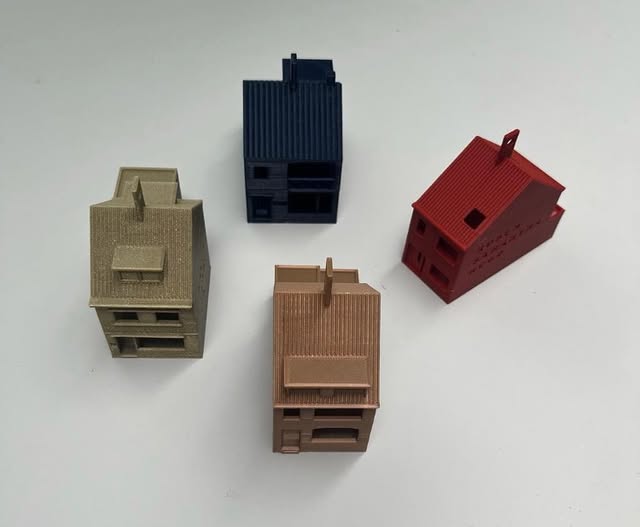 Vier geprinte huizen in goud, koper, blauw en rood